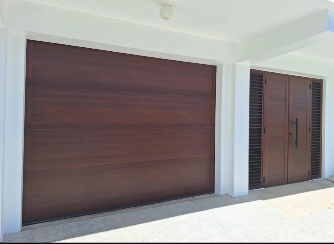 Puerta de garaje de acabado tipo madera junto a puerta de entrada en una residencia.